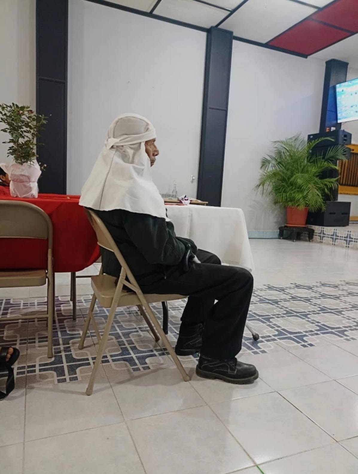 Persona sentada en el interior del lugar de reunión.
