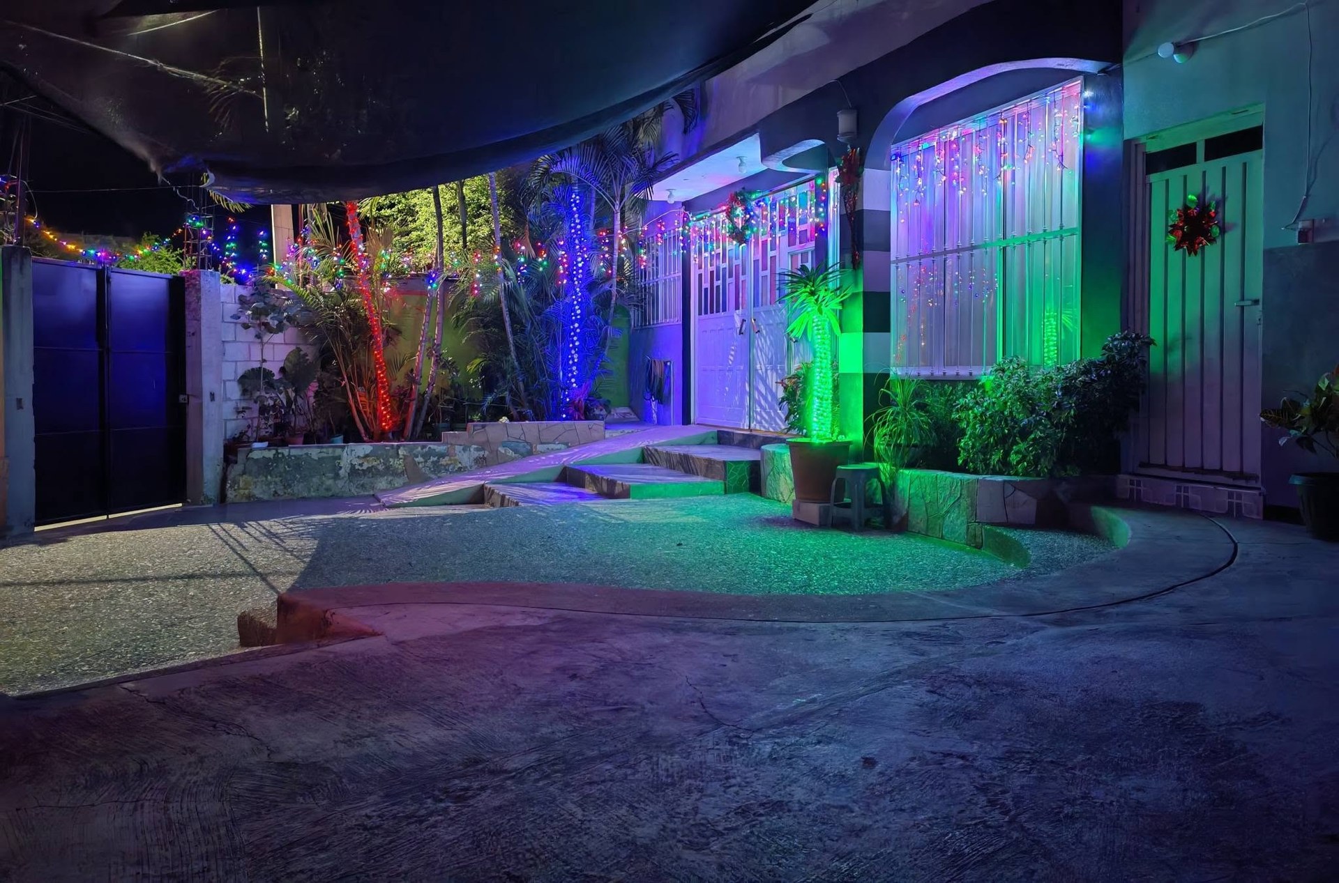Vista nocturna de la entrada y el patio con luces de colores.